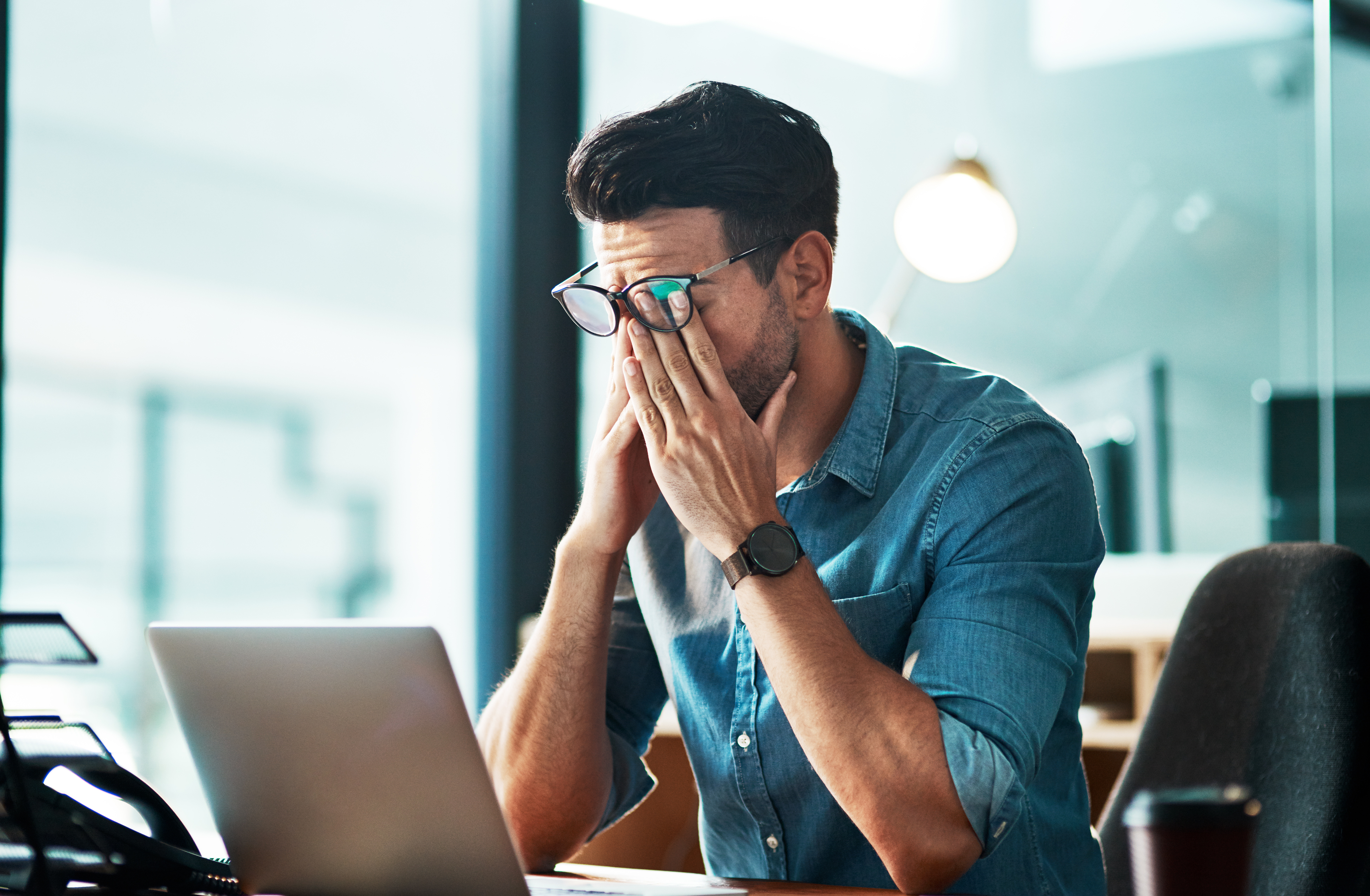 Man rubbing his eyes laptop computer frustration tired