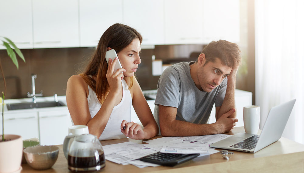 Frustrated couple on phone and laptop computer Frustrated couple on phone and laptop computer
