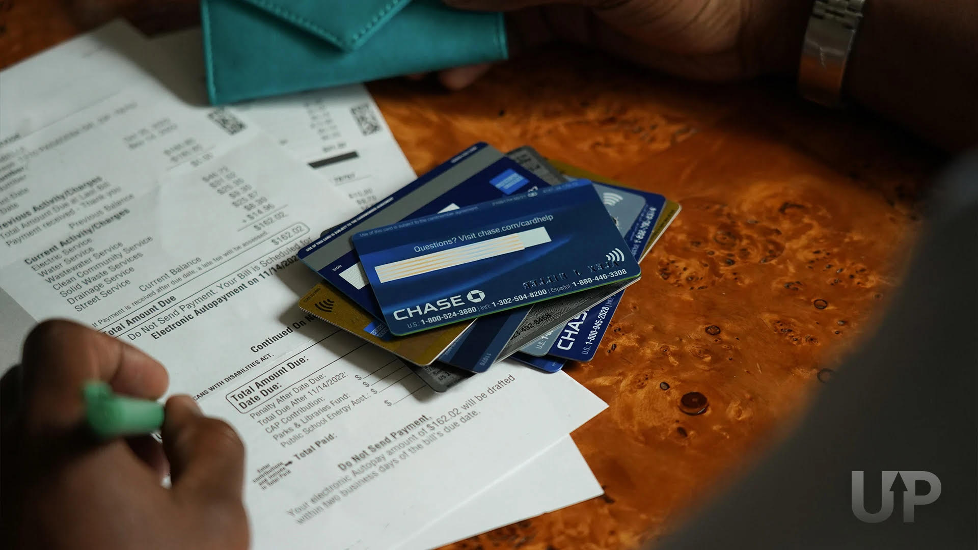 Stack of Credit Cards on top of utility bills Upgraded Points LLC 