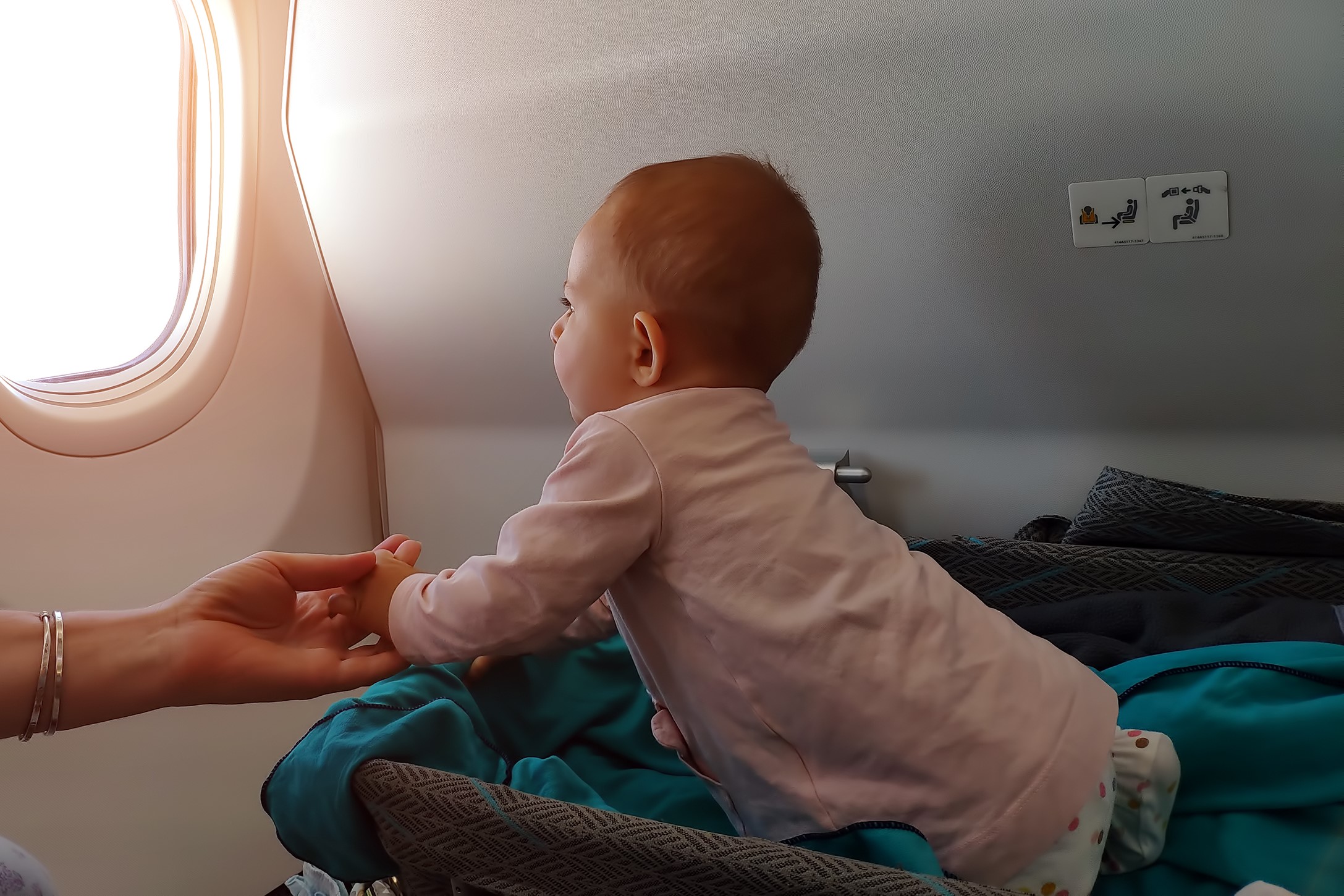 Baby looking out airplane window in bassinet