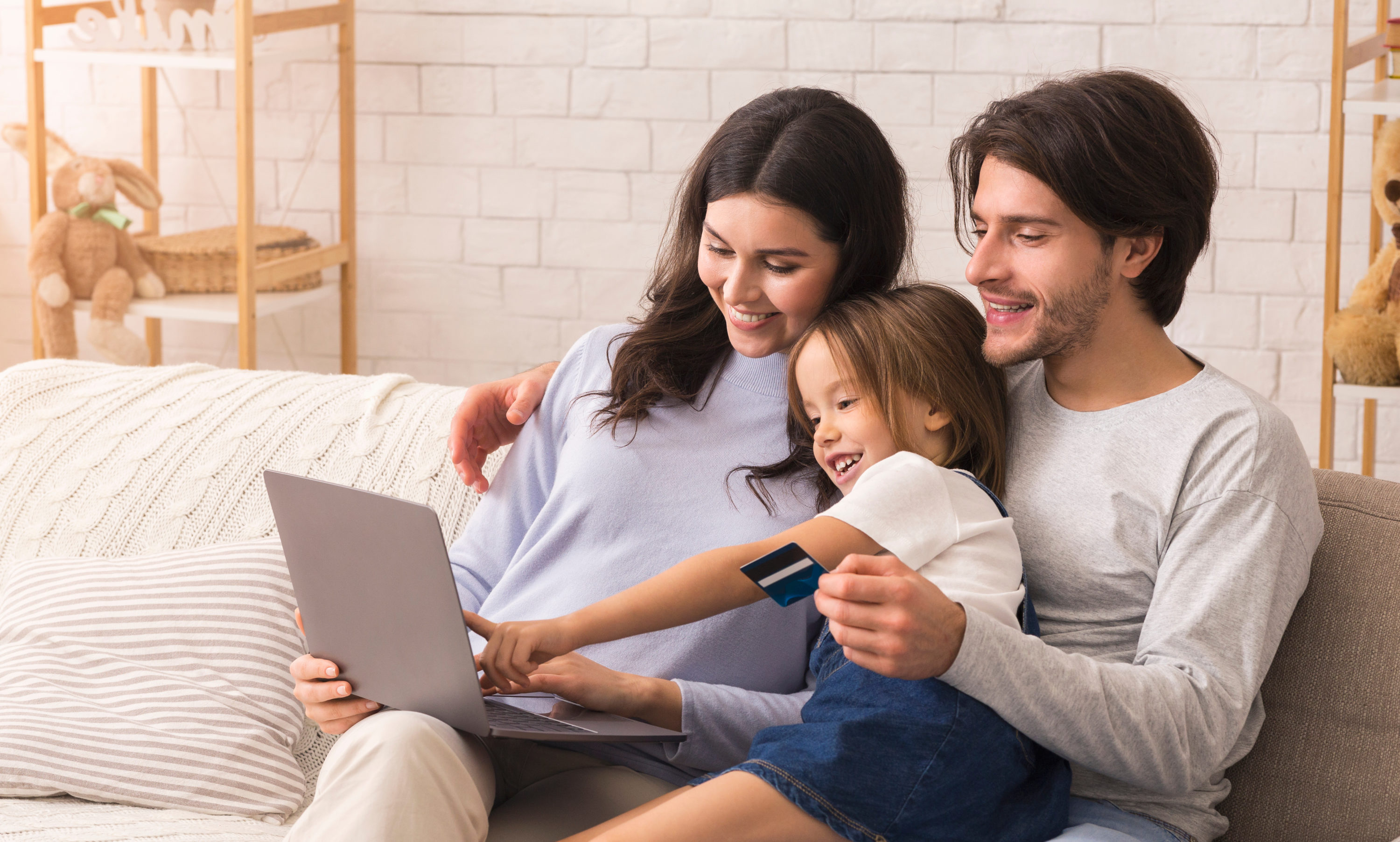 Family girl and parents using laptop with credit card
