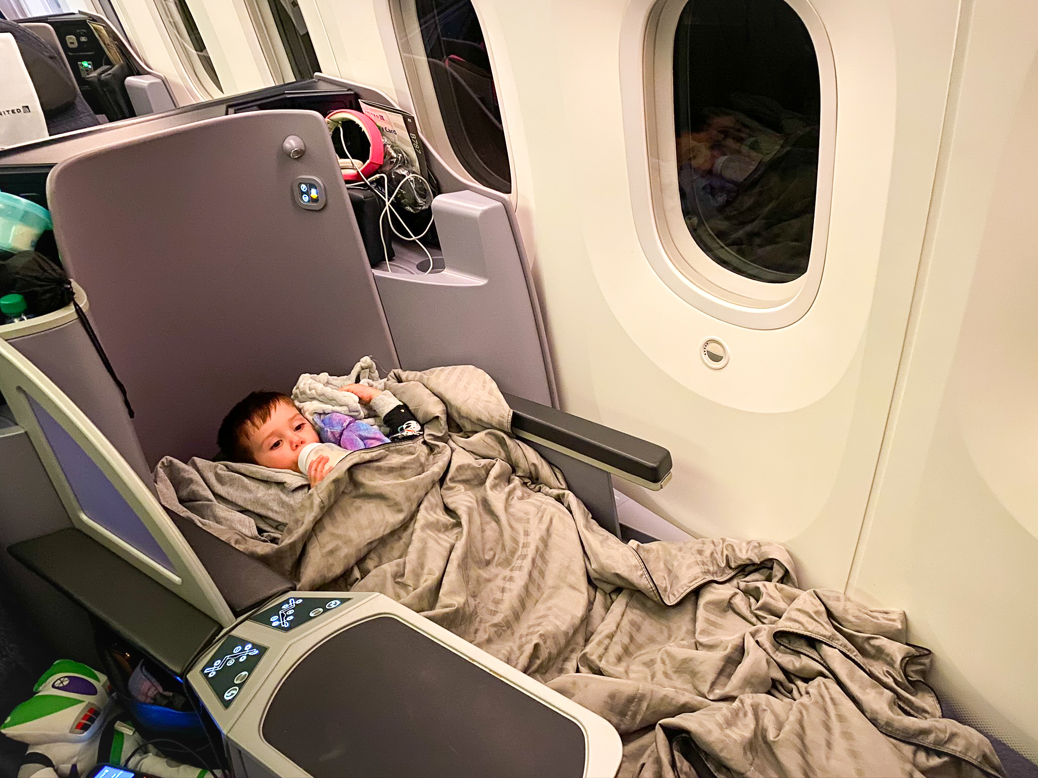 Toddler drinking bottle of milk in United Boeing 787 Dreamliner Polaris Business Class