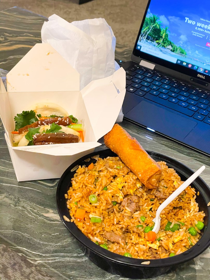 Takeout Chinese food next to a black Dell laptop
