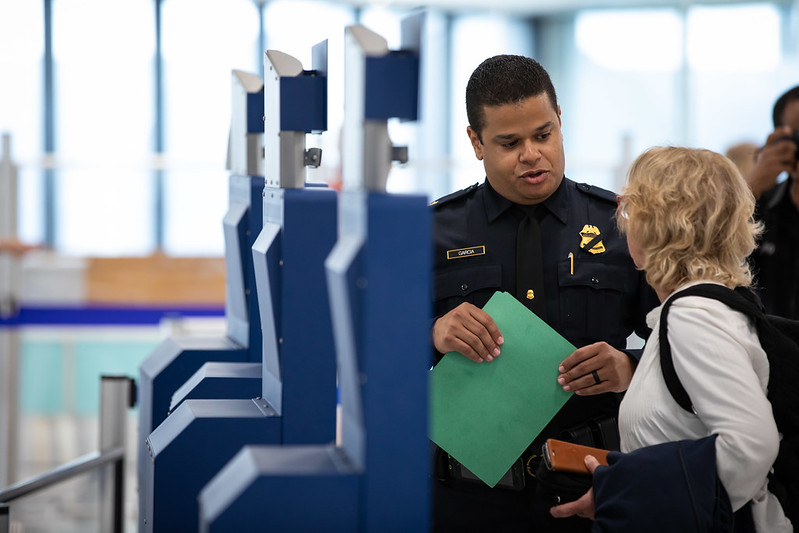 Woman using Global Entry kiosk with CBP agent Woman using Global Entry kiosk with CBP agent