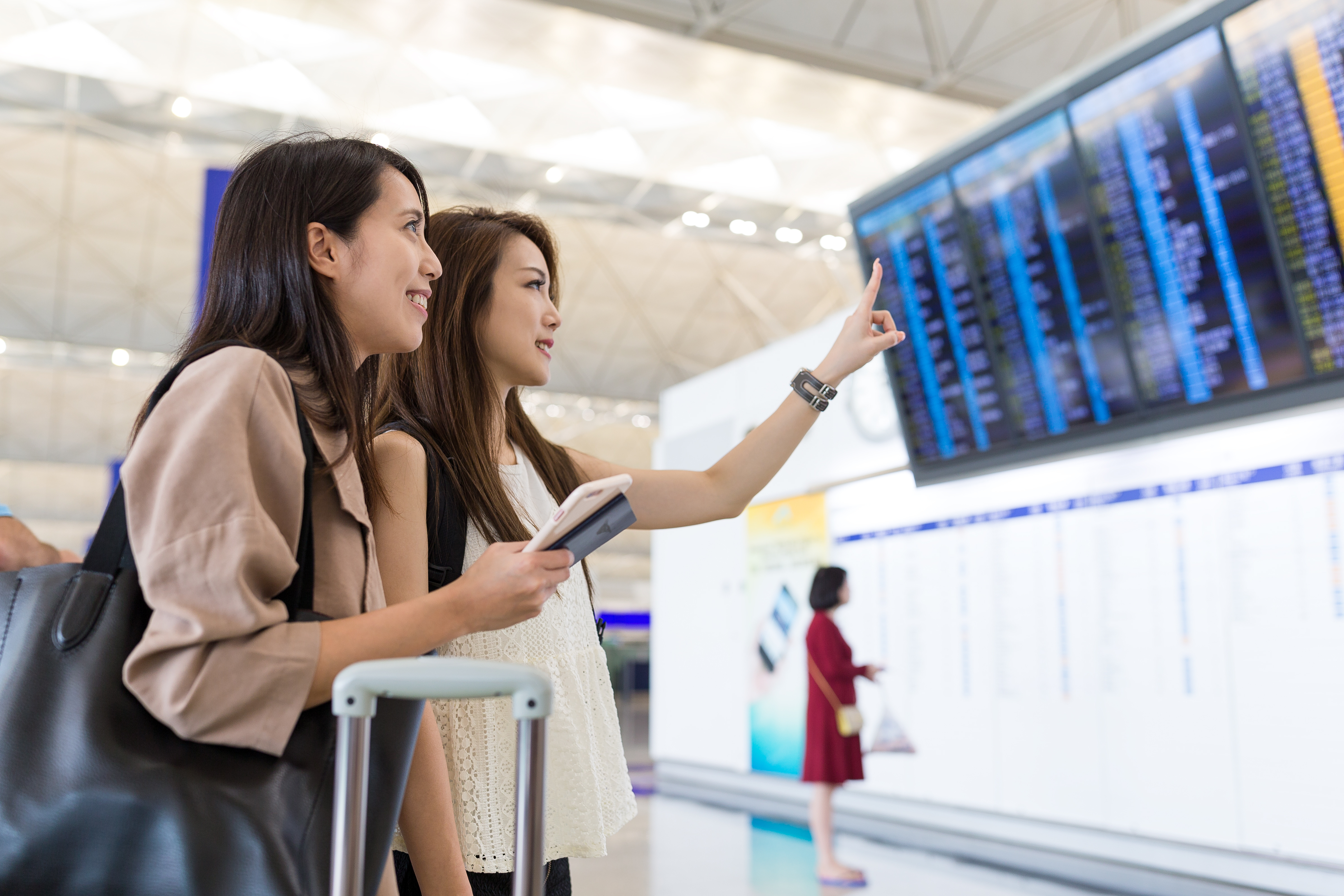 friends at airport looking at departure board