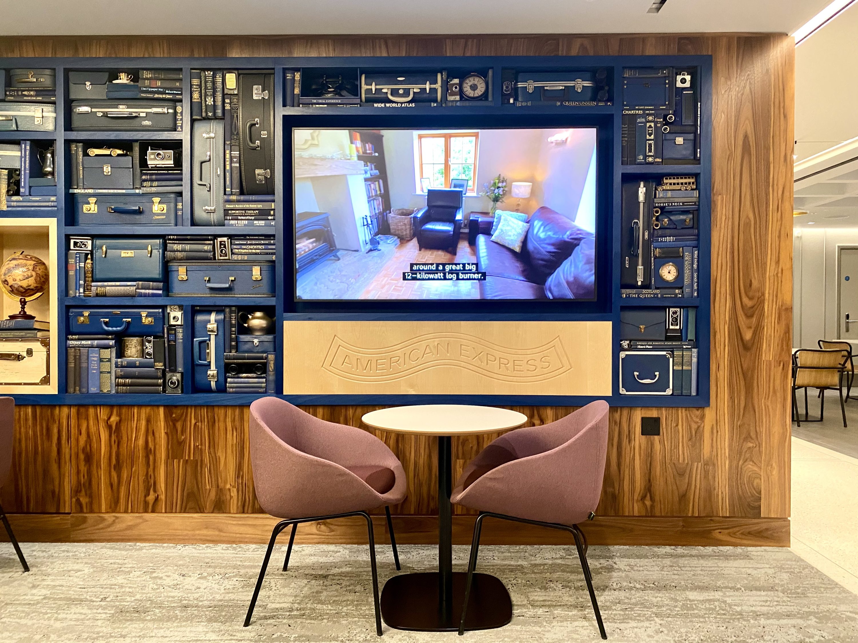 American Express Centurion Lounge Heathrow Terminal 3 TV and Amex travel decor A TV, a table, and two chairs inside an Amex Centurion Lounge.