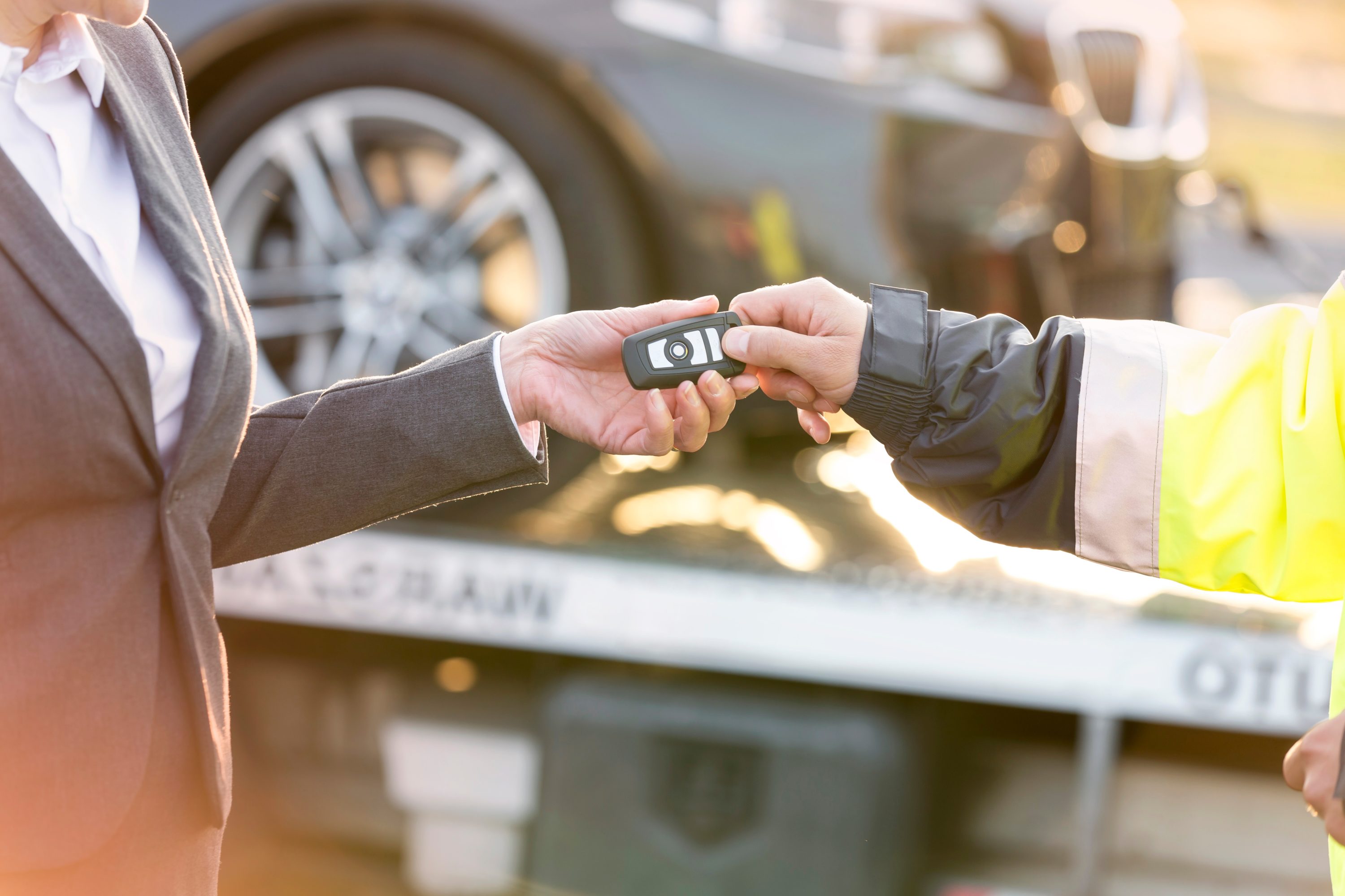 Businesswoman giving her keys to tow truck driver