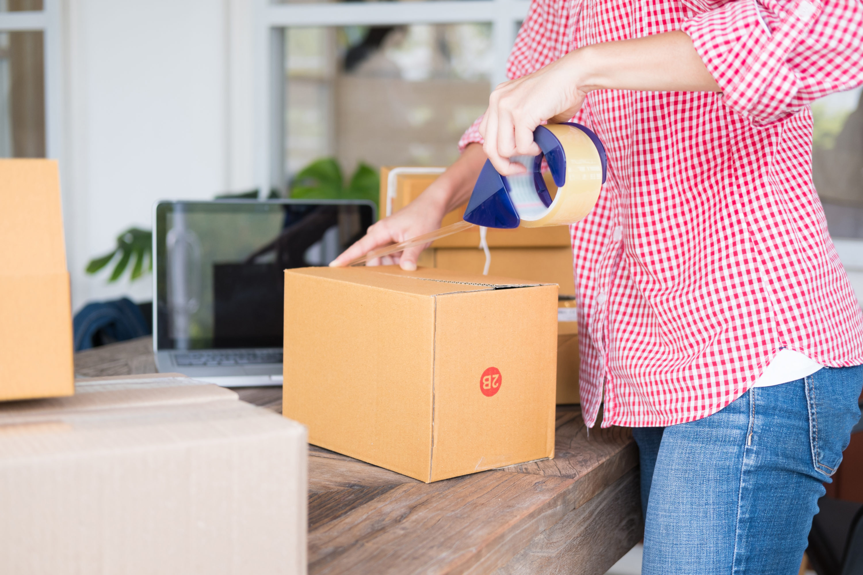 young start up small business owner packing cardboard box at workplace. freelance woman entrepreneur SME seller prepare parcel box of product for deliver to customer. Online selling, internet marketing, e-commerce, shipping concept