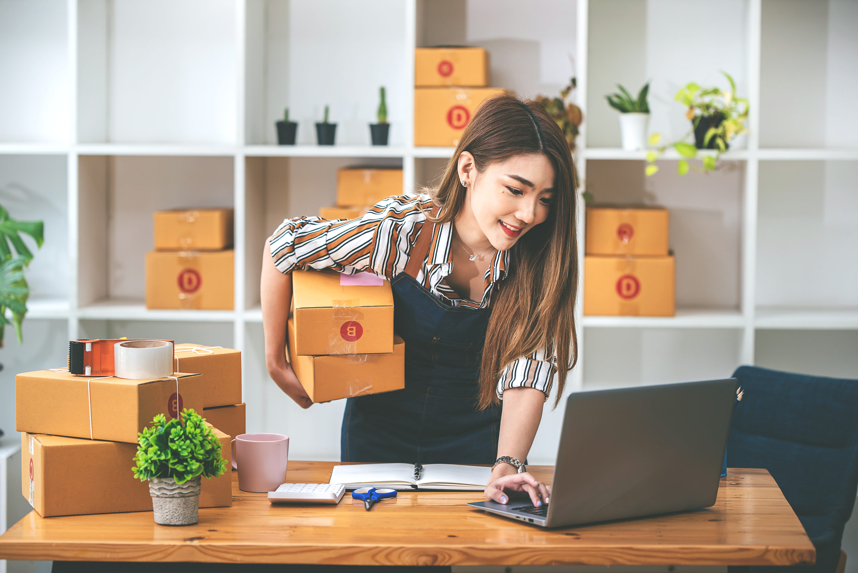 Small business owner checking laptop with boxes