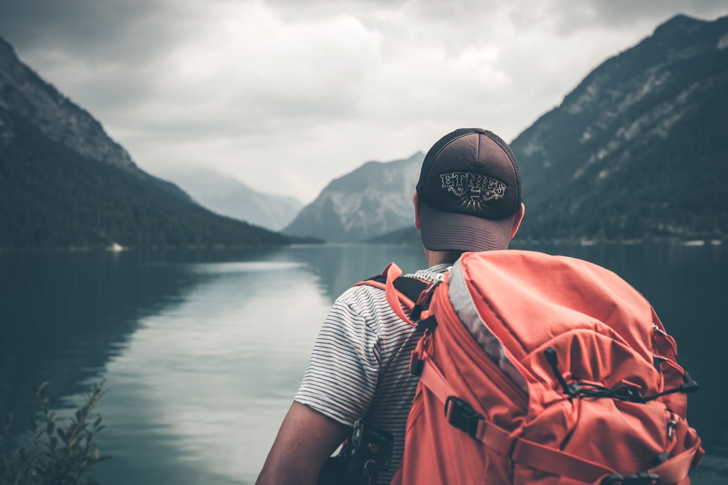 Traveler with backpack looking out across lake