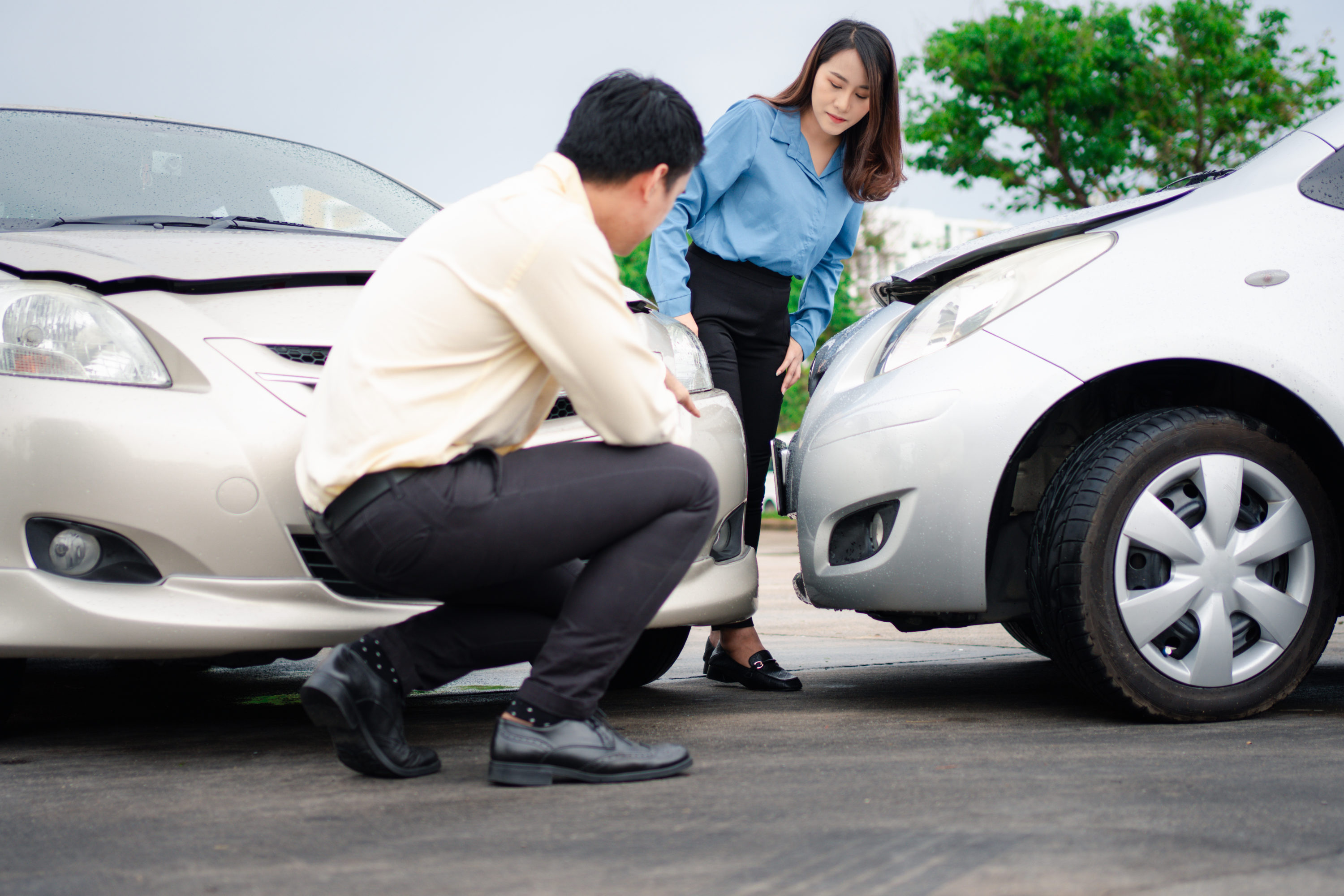 Two drivers check for damage after a car accident before taking pictures and sending insurance