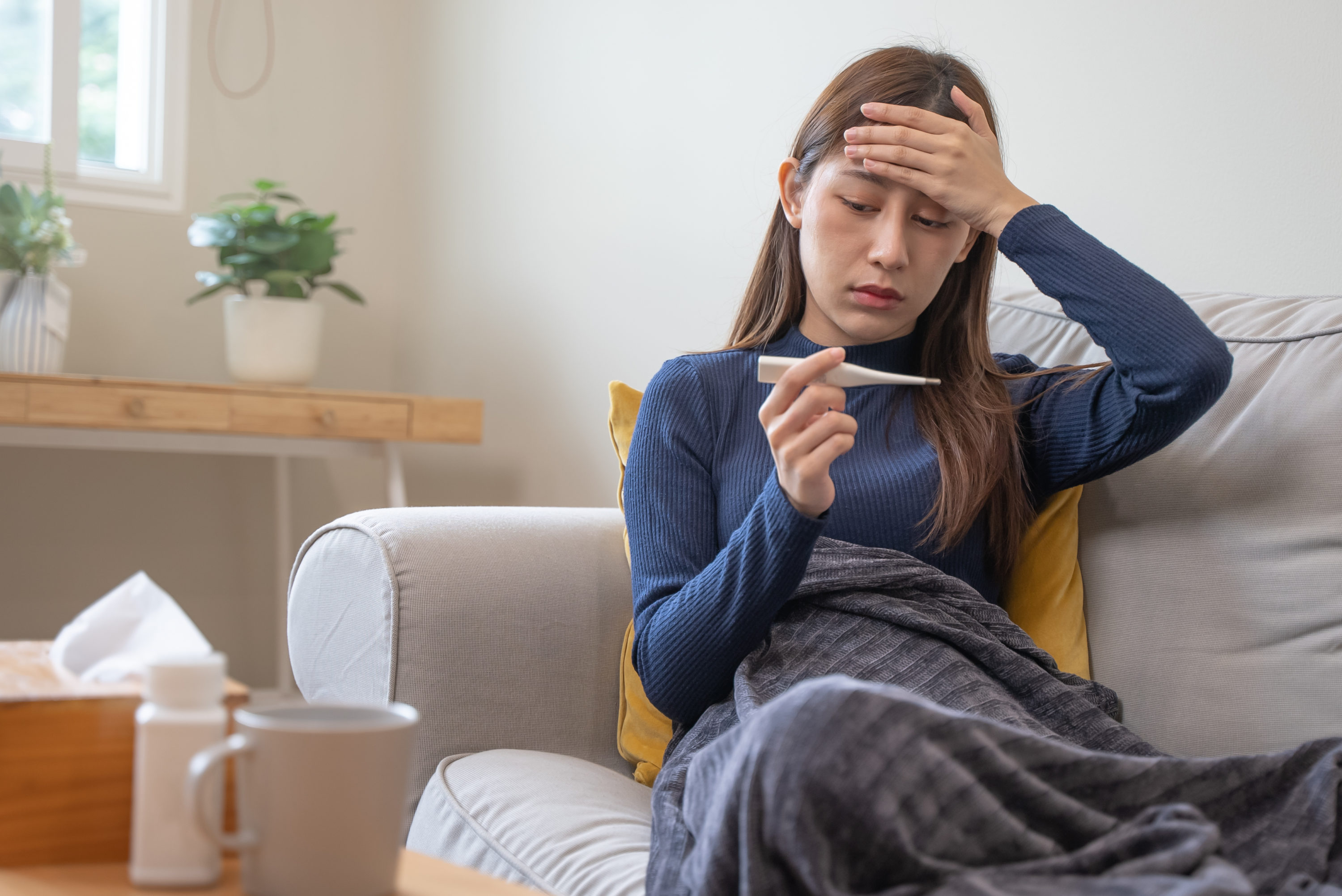 Sick woman checking temperature at home