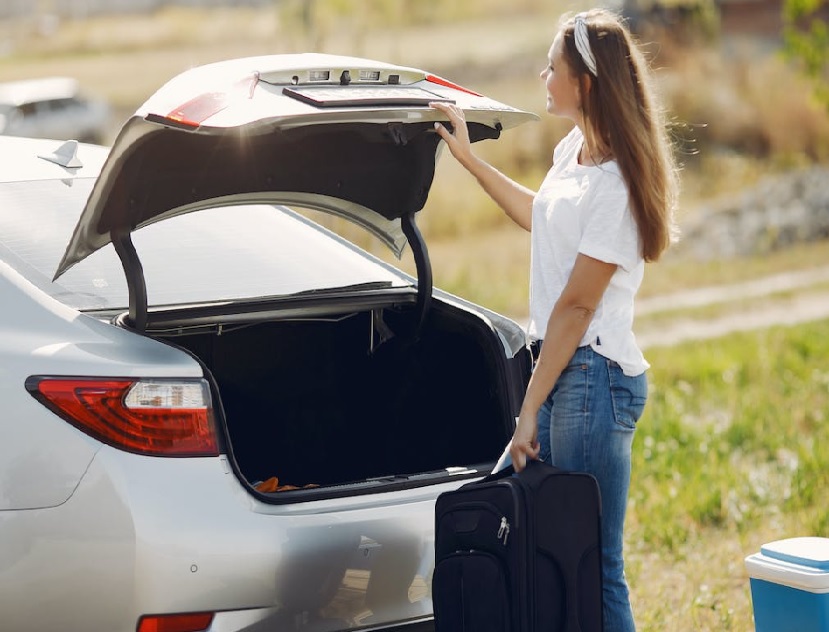 Woman loading bag in car trunk Woman loading bag in car trunk
