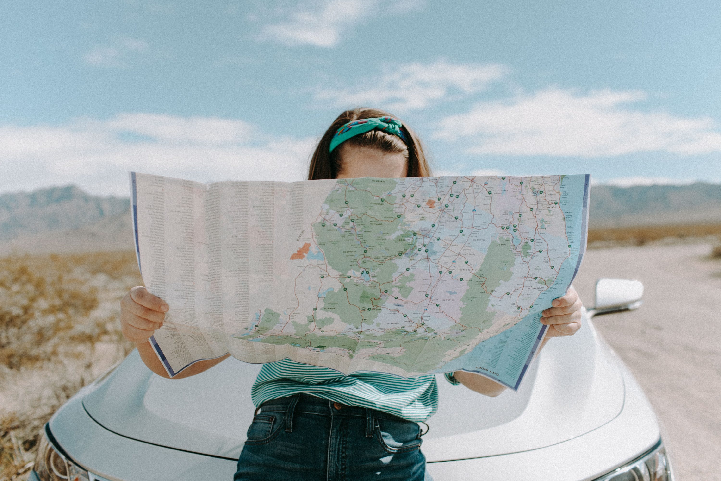 Woman looking at map on car hood
