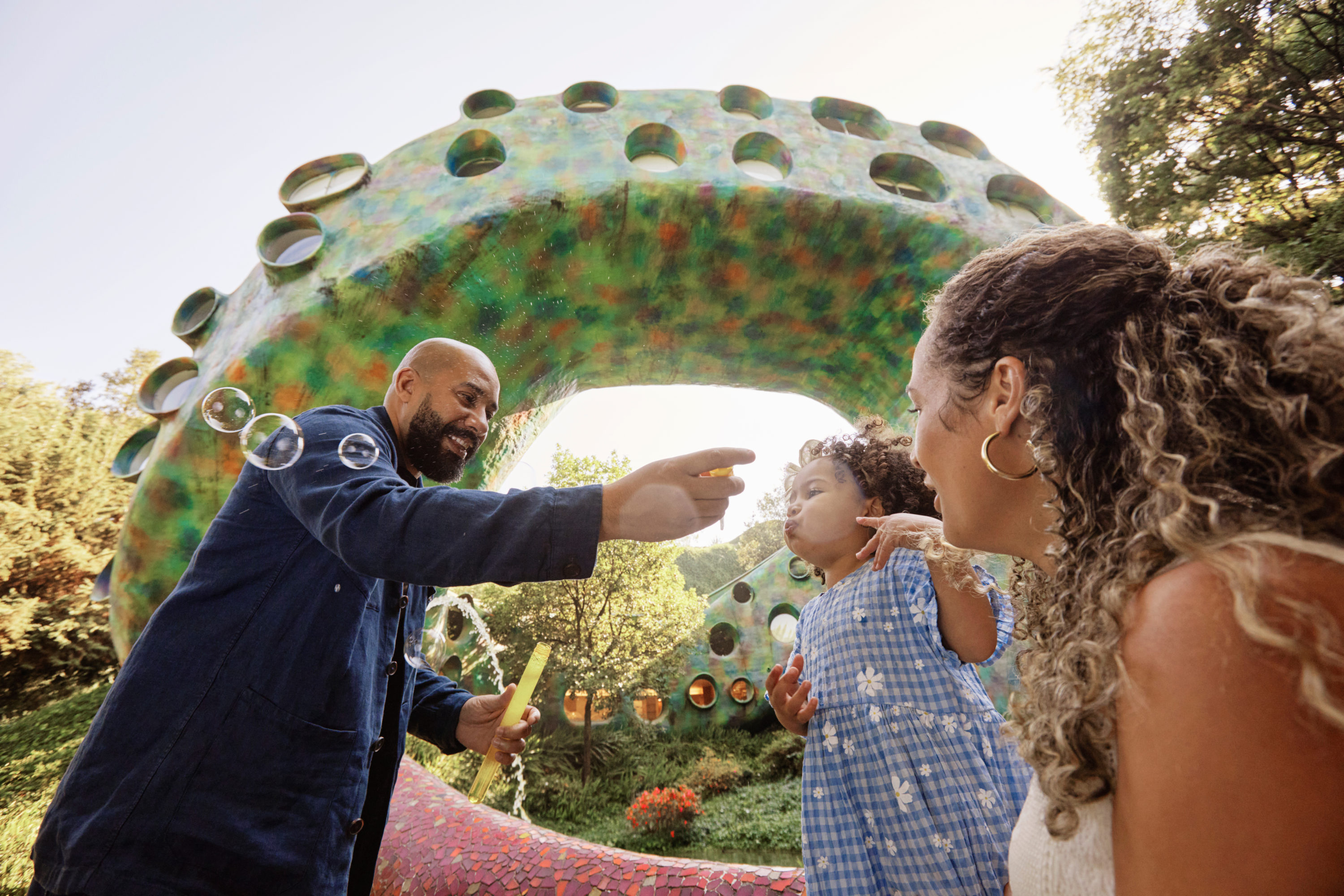 Family in garden park blowing bubbles.