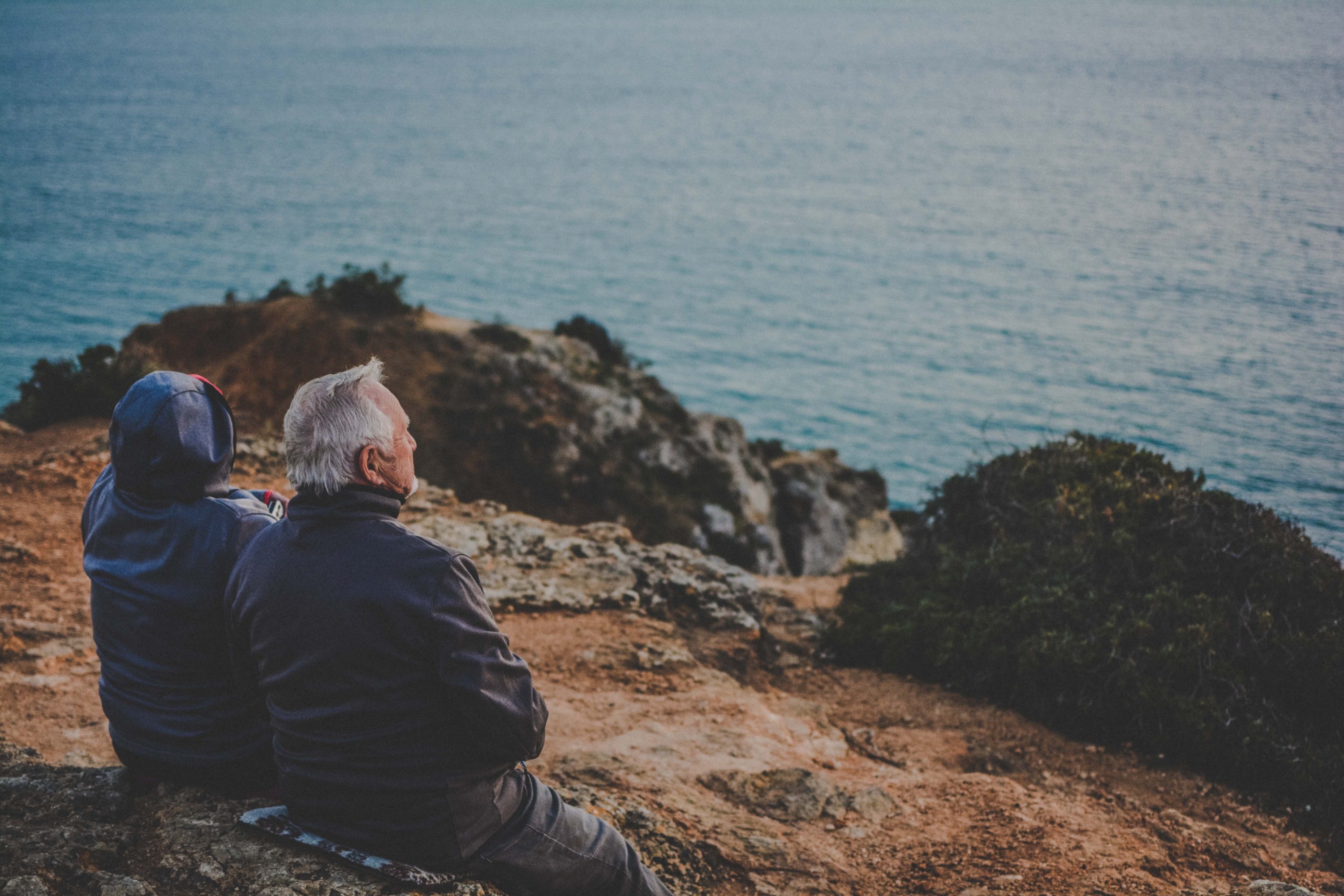 Old couple sitting next to each other looking off in the distance Older couple sitting next to each other looking off in the distance