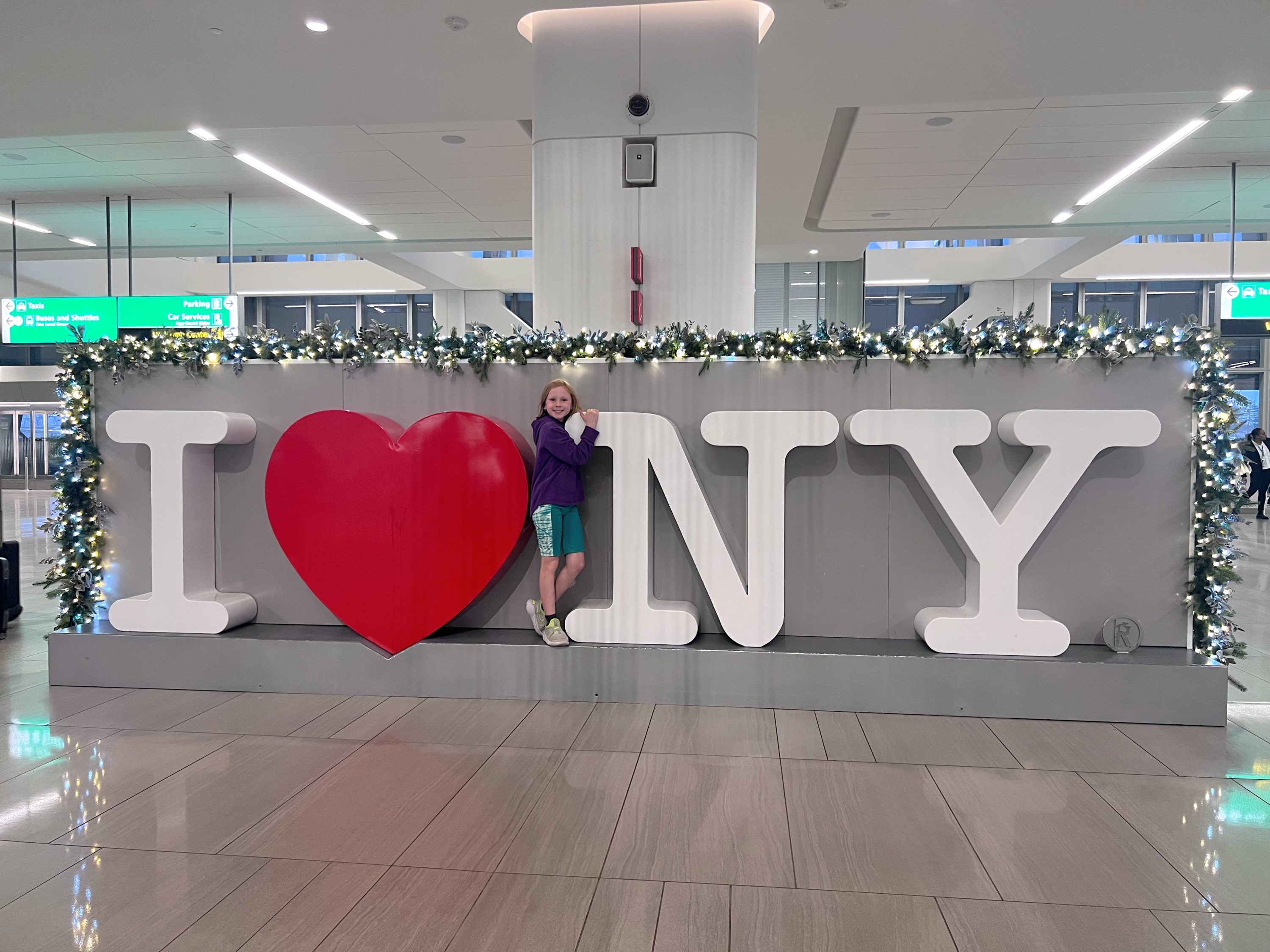 child standing by the I Love NY sign at LaGuardia airport child standing by the I Love NY sign at LaGuardia airport