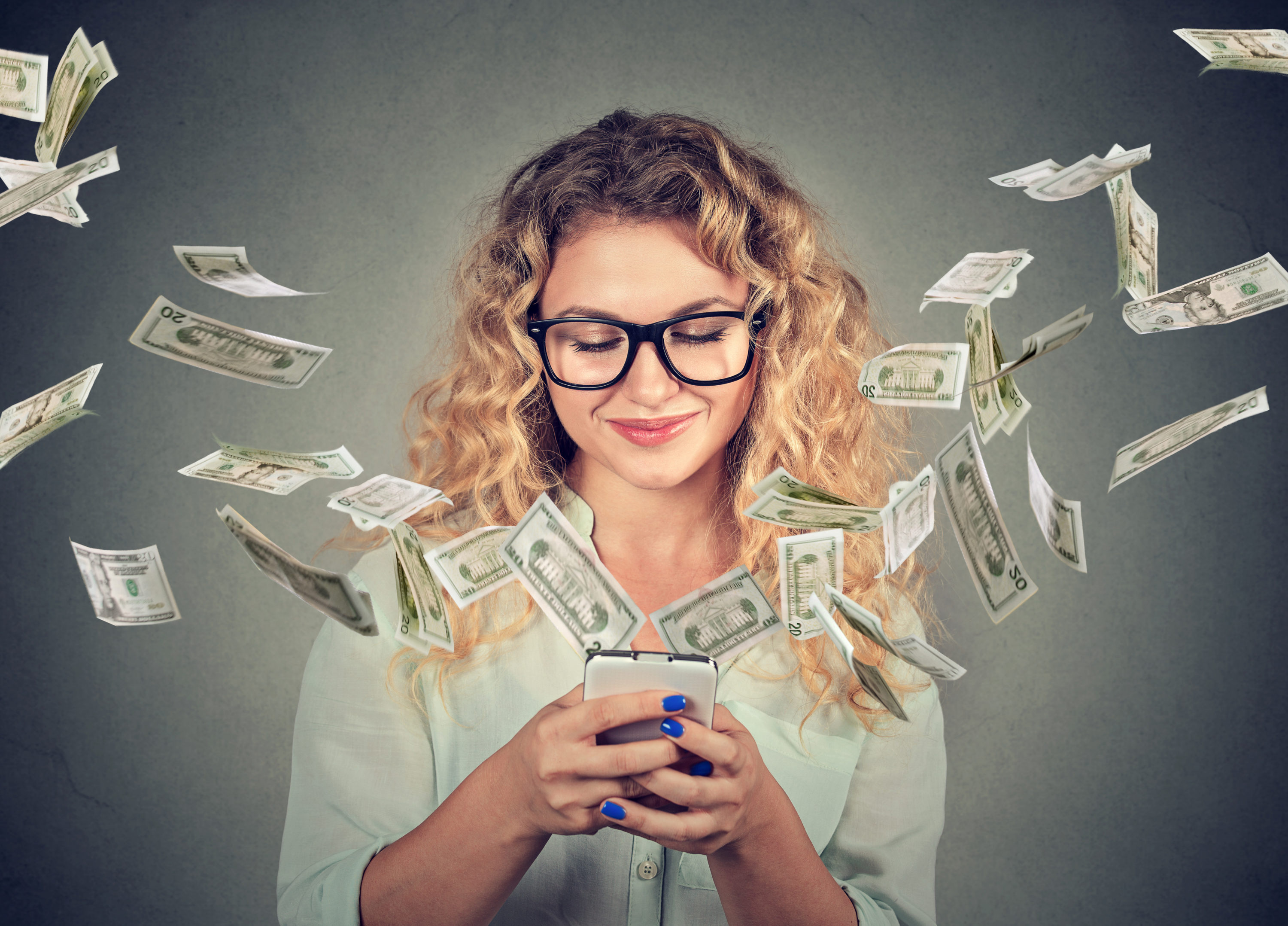Woman using phone with dollar bills flying away from screen