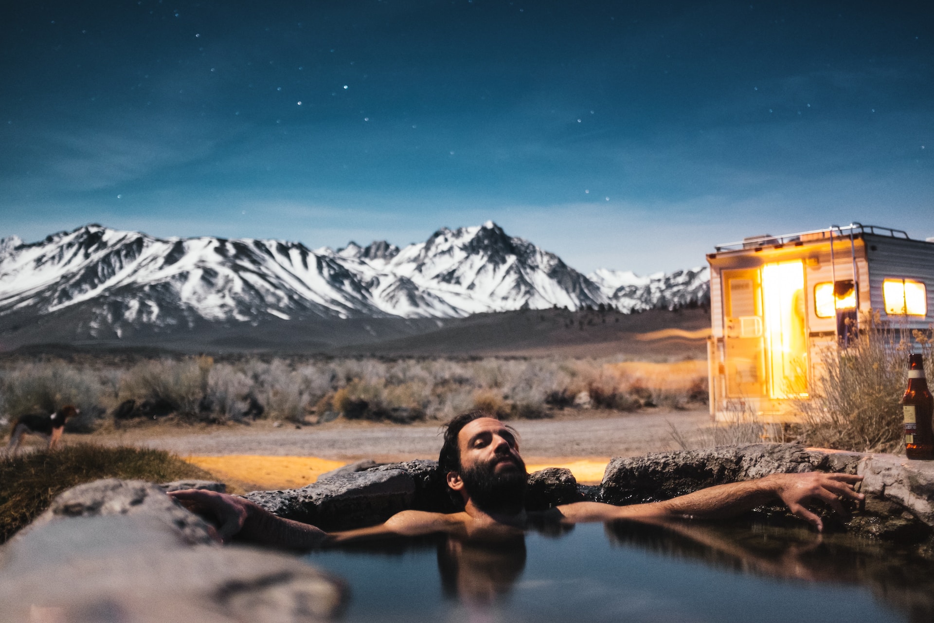 A man soaking in an outdoor natural pool Mountains and man in a pool