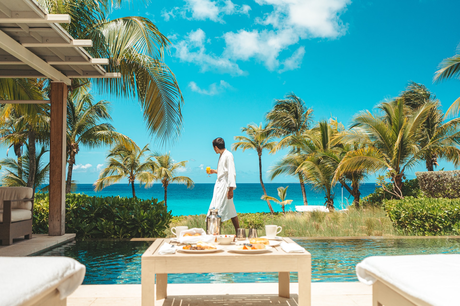 A man walks by a pool holding orange juice