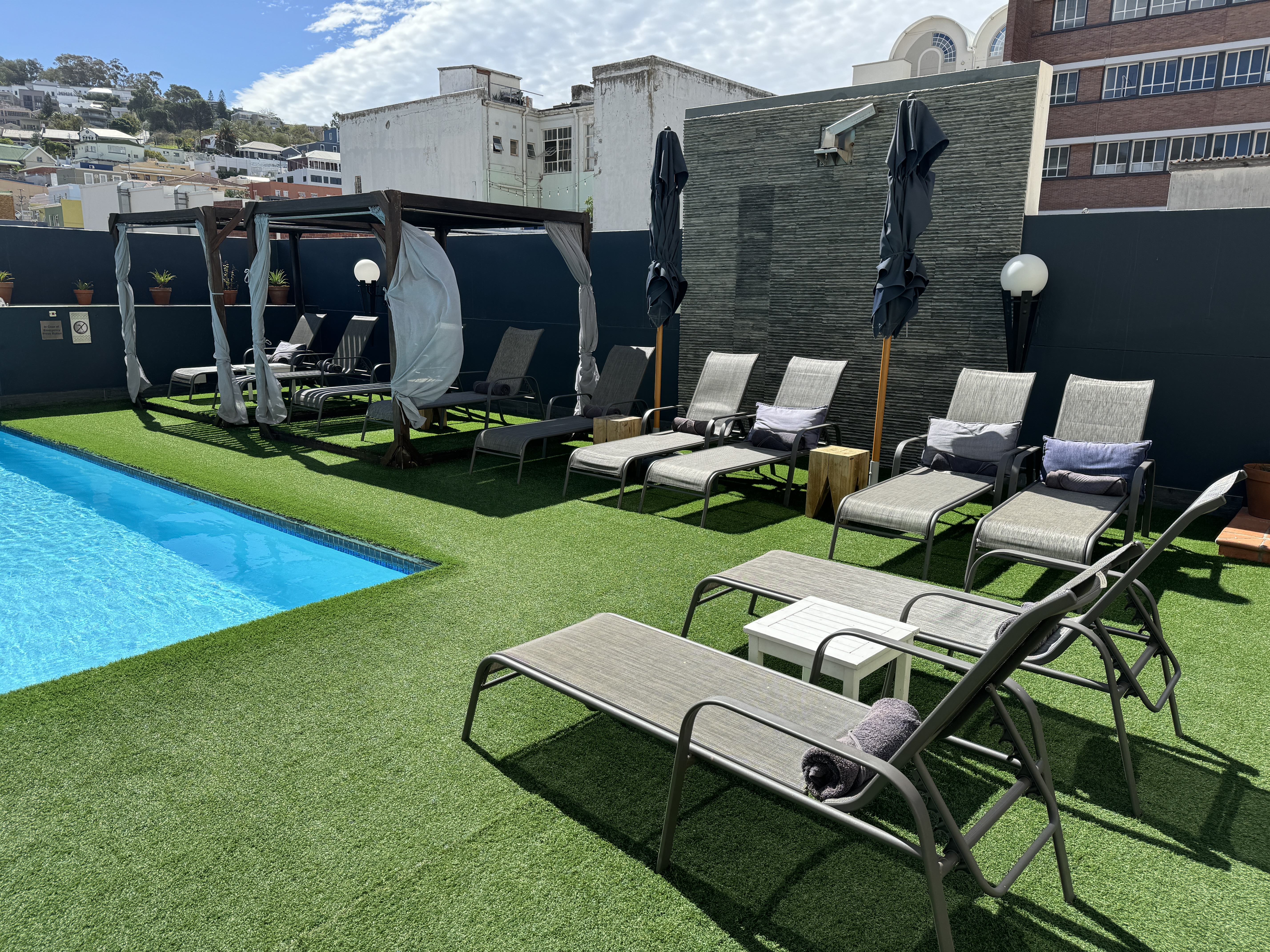 Hyatt Regency Cape Town pool lounge area Hyatt Regency Cape Town pool area with dark grey cabanas with white sheets and grey lounge chairs.
