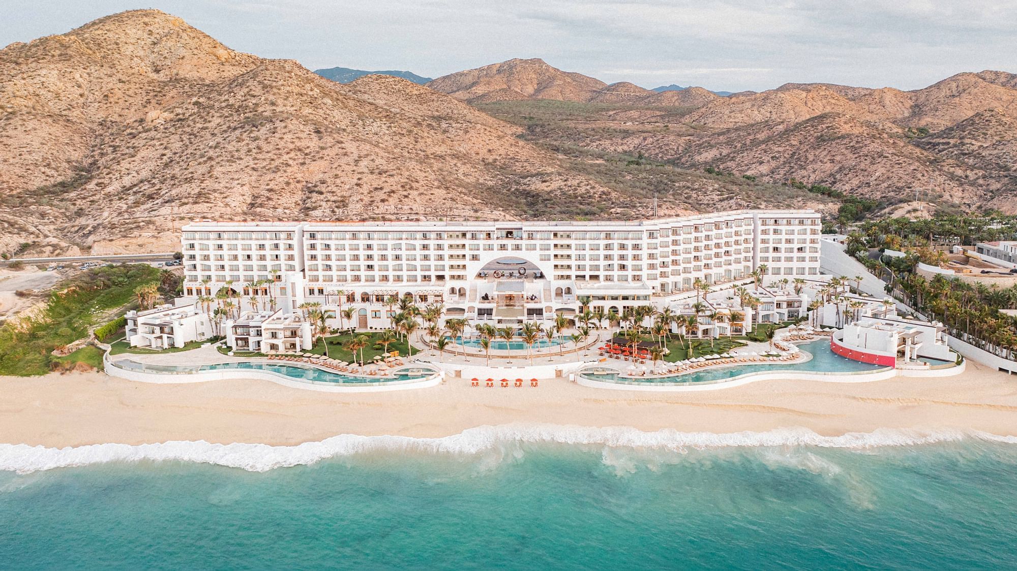Marquis Los Cabos A photo of Marquis Los Cabos from the ocean featuring 3 pools and hills in the background.