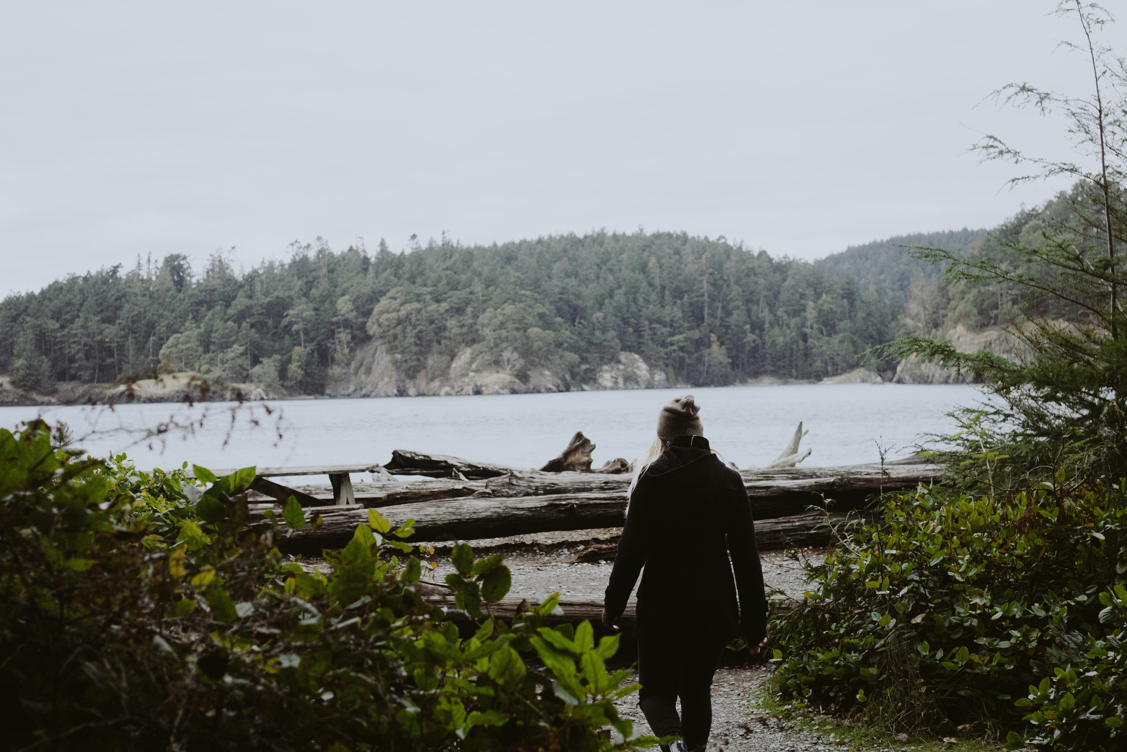 Woman walking toward water at Deception Pass State Park Woman walking toward water at Deception Pass State Park