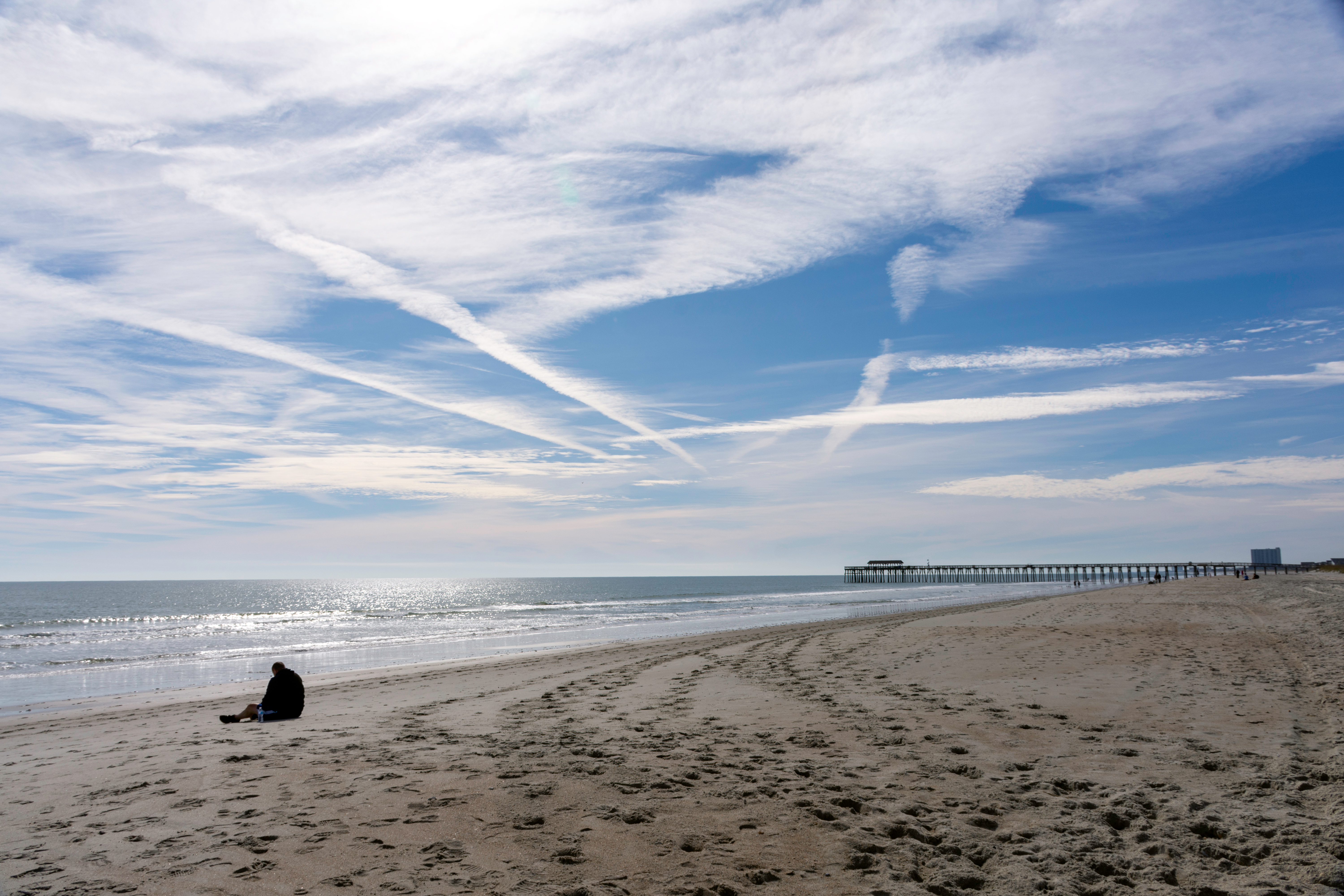 View of the beach, ocean, clouds and a man at Myrtle Beach State Park, in South Carolina, USA. View of the beach, ocean, clouds and a man at Myrtle Beach State Park, in South Carolina, USA.