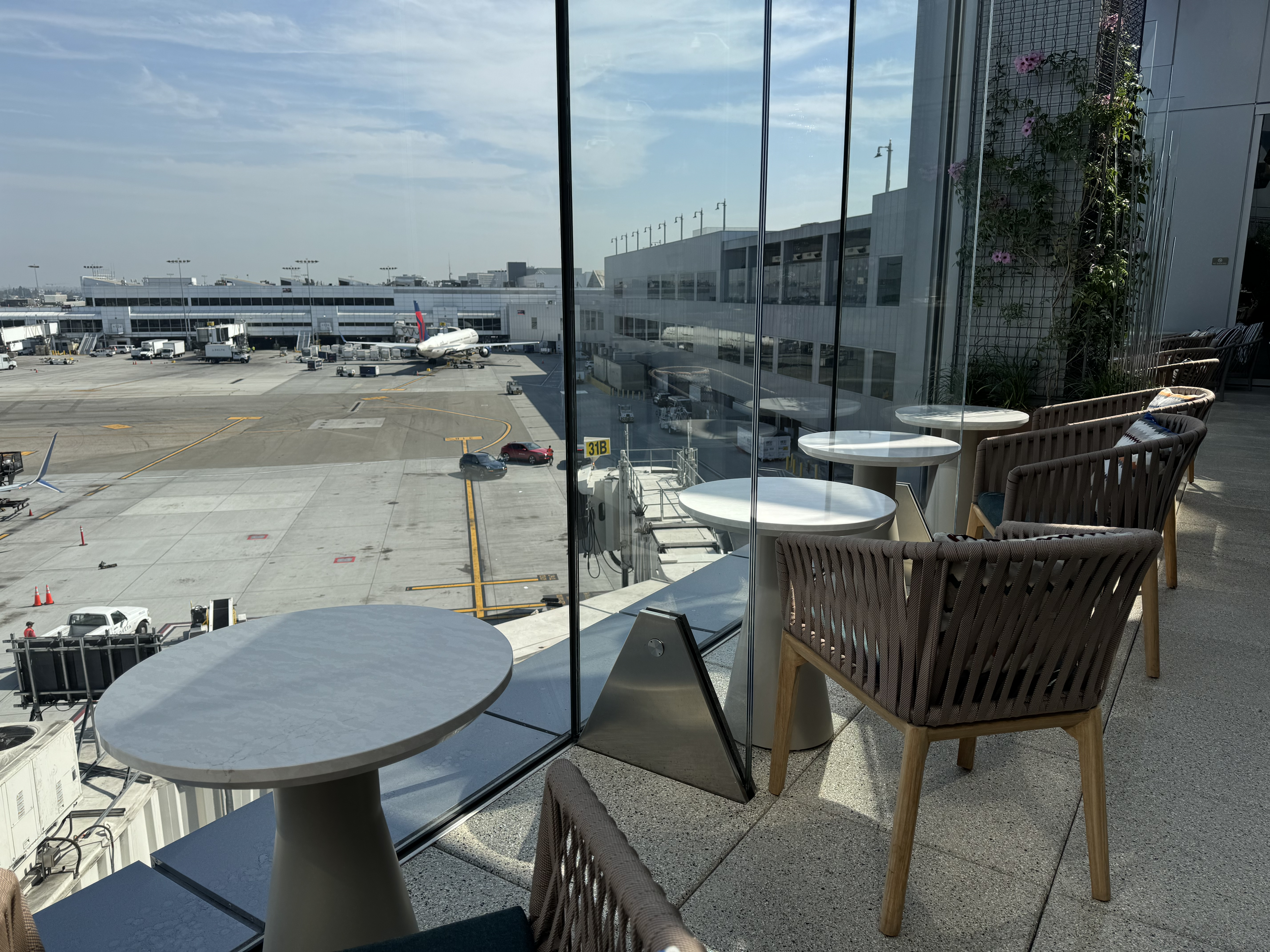 Delta One Lounge LAX terrace seating at glass panel Delta One Lounge LAX terrace seating at glass panel