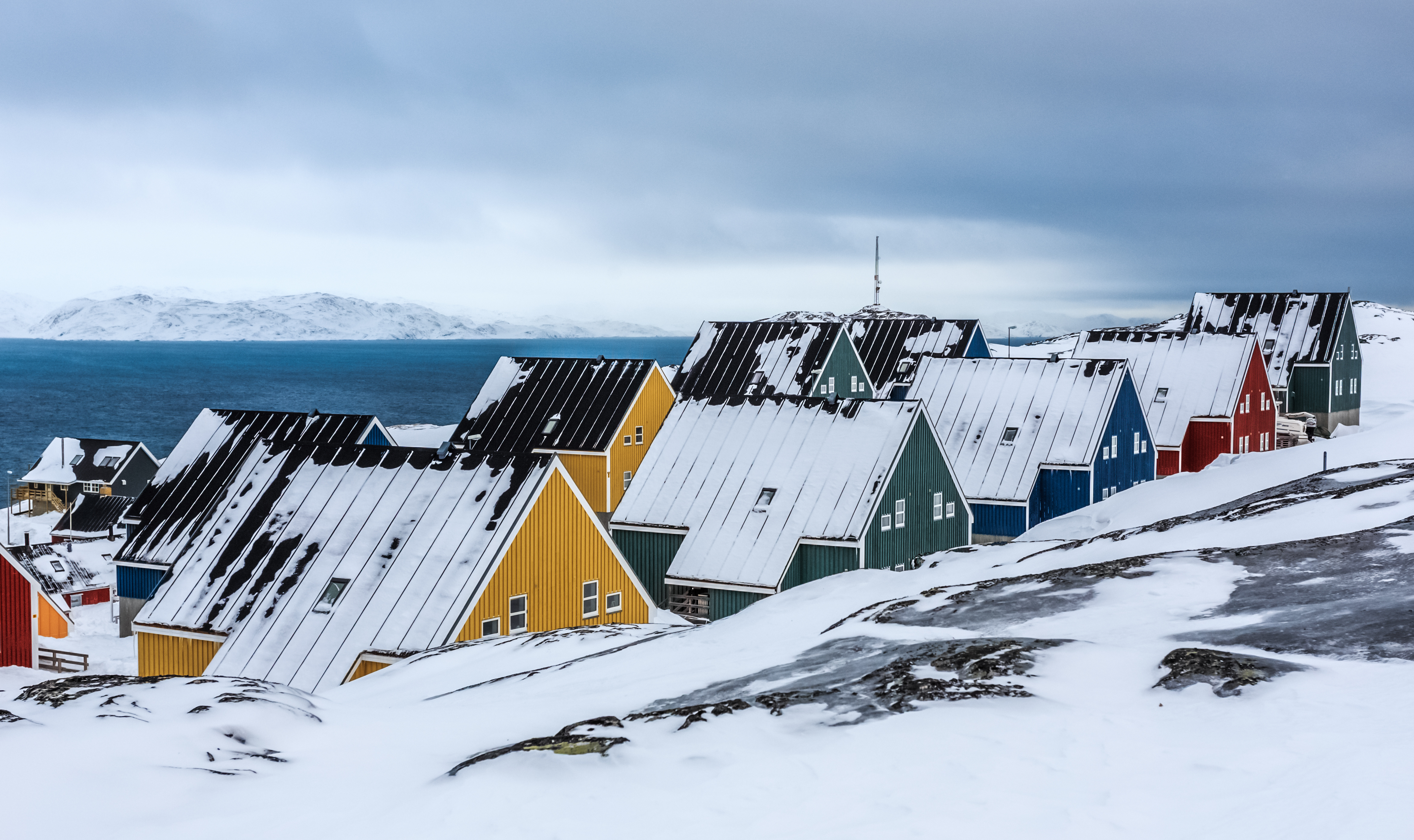 Yellow, blue, red and green inuit houses covered in snow at the fjord of Nuuk city, Greenland Yellow, blue, red and green inuit houses covered in snow at the fjord of Nuuk city, Greenland