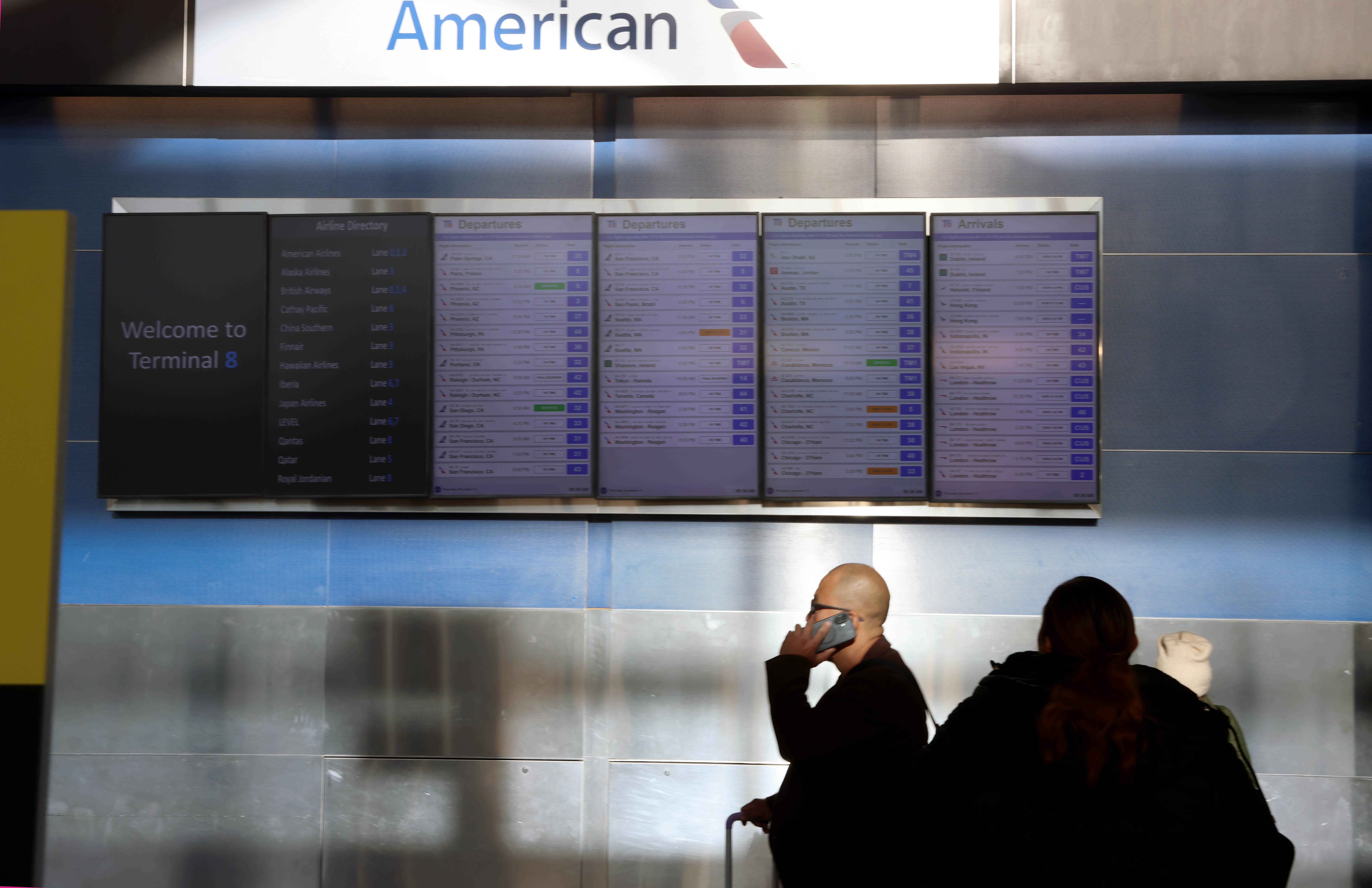 JFK airport AA departures board man phone JFK airport AA departures board man phone